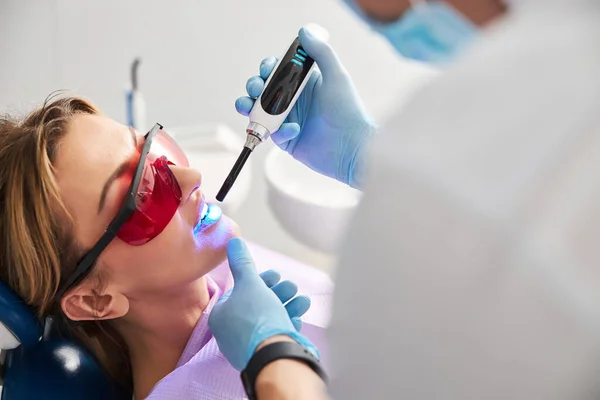 Stomatologist setting dental sealants in person teeth