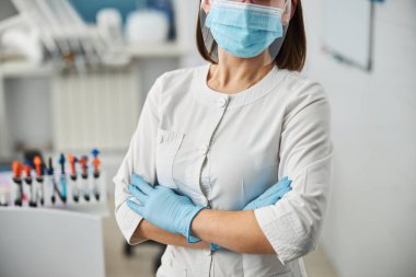 Doktor odasında kollarını kavuşturmuş diş cerrahı.