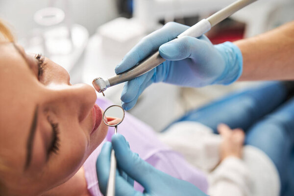 Два зубоврачебных инструмента рядом с ртом пациента