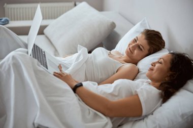 Yatakta film izleyen iki neşeli kadın.