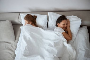 İki mutlu kadın, yumuşak battaniyenin altında yatıyor.