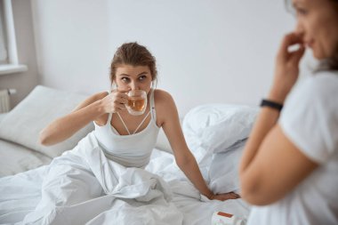 Hüsrana uğramış kadın yatakta sıcak çay içiyor.