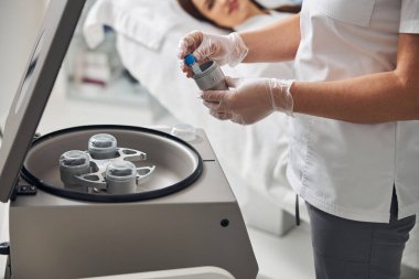 Kadın doktor elleri metal kutuya test tüpü yerleştiriyor.