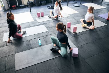 Atletik kadınlar antrenörleri tarafından eğitildiği gibi esniyorlar.