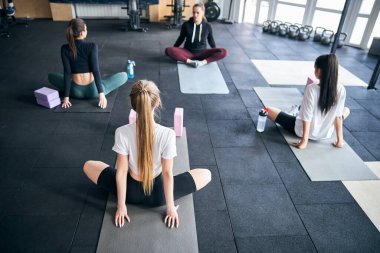 Formda kadınlar spor salonunda kalça kaslarını esnetiyor.