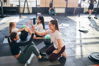 Pozitif kadınlar spor salonunda karın kası egzersizi yapıyor.