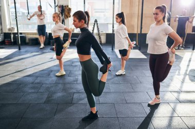 Ayaklarını tutup esneyen zinde genç kadınlar.