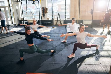 Konsantre ve zinde kadınlar spor salonunda yoga pozu veriyorlar.