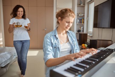 Nazik esmer kadın çaydanlık ve bardak taşıyor.