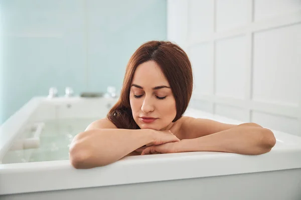 Peaceful woman laying head on her arms in jacuzzi