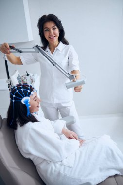 Laboratuvar önlüklü arkadaş canlısı doktor elektroansefalografiyi gerçekleştiriyor.