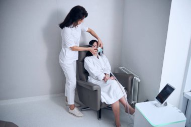 Koyu renk saçlı genç bir kadın oksijen tedavisi görüyor.