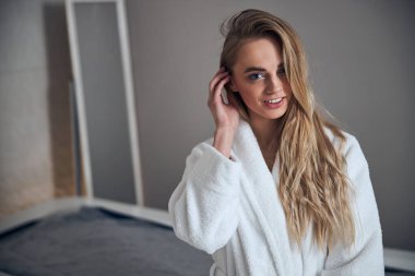 Terry bornozlu hasta masaj odasında oturuyor.