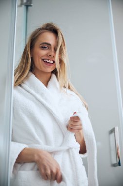 Ön tarafta bornoz kemerini bağlayan neşeli bayan.