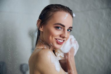 Neşeli genç kadın duş odasında kendini yıkıyor.