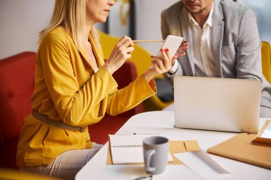 Dikkatli sarışın kadın akıllı telefon ekranını işaret ediyor.