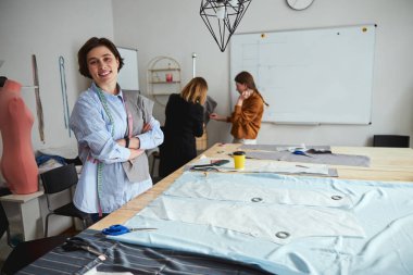 Kumaş dikerken pezonun yanında duran gururlu kadın.