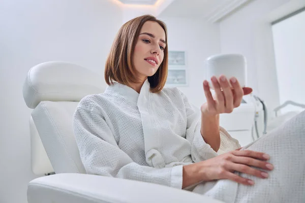 Happy cheerful young female in white bathrobe enjoying good weekend in spa resort center — Stock Photo, Image