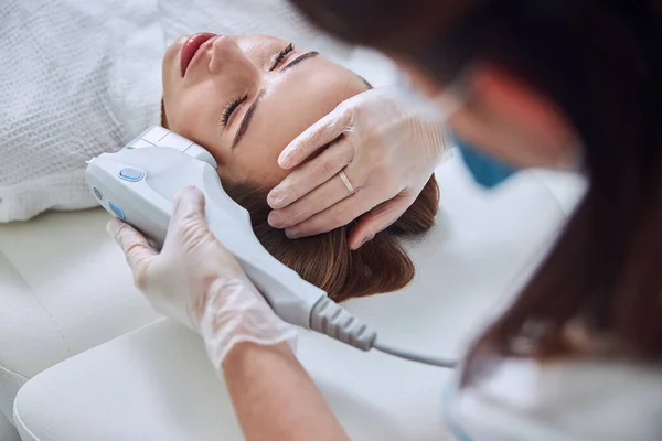 Esteticista no reconocido haciendo tratamiento de la piel del balneario en la cara del cliente femenino en el salón de spa —  Fotos de Stock