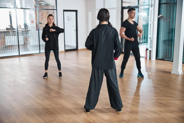 Mujer entrenador viendo más de dos estudiantes de artes marciales — Foto de Stock