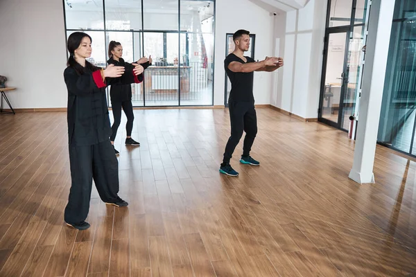 La gente sosteniendo los brazos en círculo mientras hace la pose de taijiquan —  Fotos de Stock