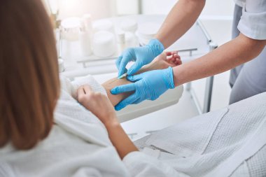 Beyaz bornozlu, tanınmayan bir kadın sağlık kliniğinde profesyonel IV infüzyon alıyor.