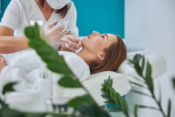 Elegant pretty female in white bathrobe getting beauty injection — Stock Photo, Image