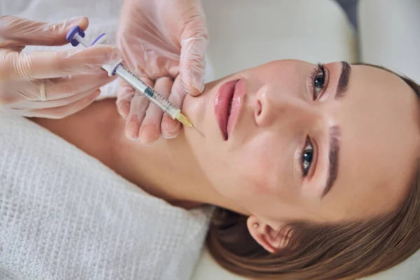 Mulher caucasiana encantadora com olhos cinzentos recebendo contorno bucal com injeção de enchimento no centro cosmético — Fotografia de Stock