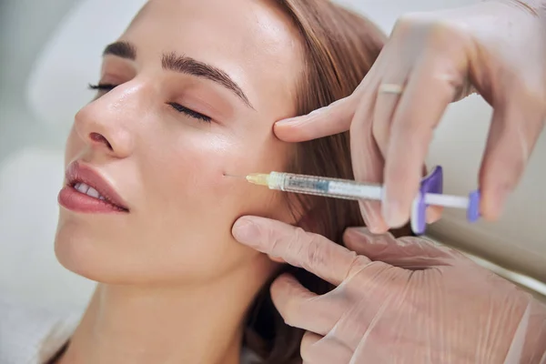 Schöne elegante Frau erhält Schönheitsoperation Injektion auf ihr Gesicht in Wellness-Salon — Stockfoto