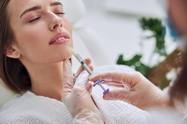 Adorable hembra caucásica en albornoz blanco recibiendo levantamiento de sonrisa y eugmentación de labios en el centro de spa — Foto de Stock