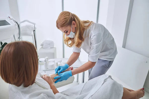 Beautiful elegant physician in white uniform during medical procedure in welness center — Stock Photo, Image