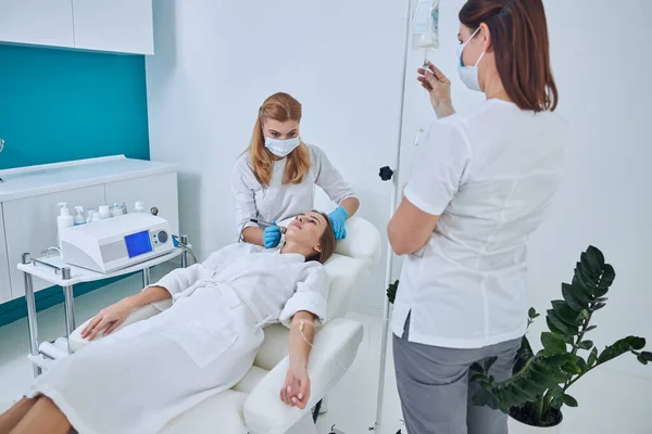 Young attractive woman in white bathrobe receiving professional skin care in beauty clinic — Zdjęcie stockowe