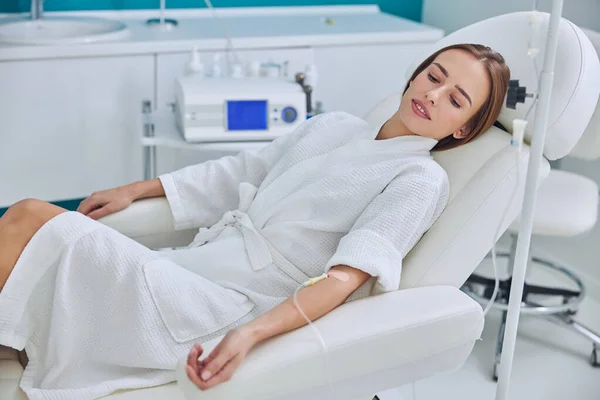 Redheaded beautiful female resting and getting IV infusion in spa salon — Zdjęcie stockowe