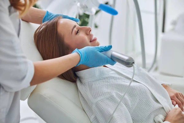 Happy funny young Caucasian female lying on medicine chair during spa beauty procedure in wellness center — Fotografia de Stock