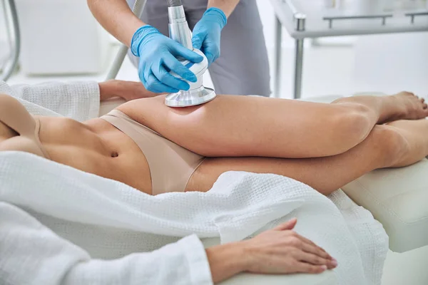 Unrecognized female in white bathrobe receiving anti-cellulite and anti-fat therapy in beauty clinic — Foto de Stock