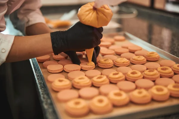 Skillful cook puttinf filling onto macarons with a confectioner syringe — Stok fotoğraf