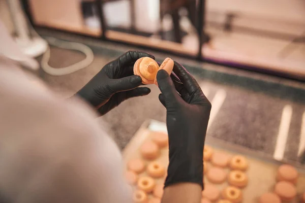 Attentive pastry chef assembling macarons in the kitchen — Stok fotoğraf