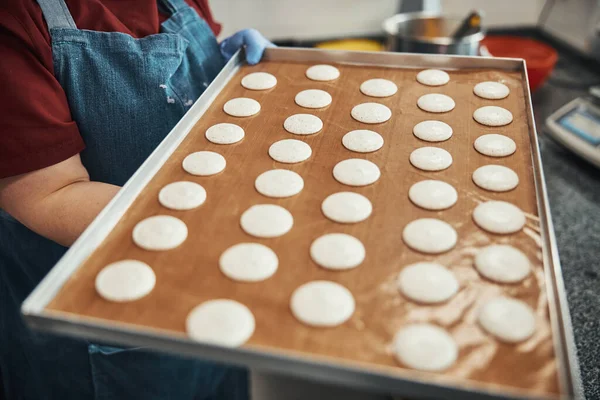 Talented cook carrying tray with macaron batter dots — Stok fotoğraf