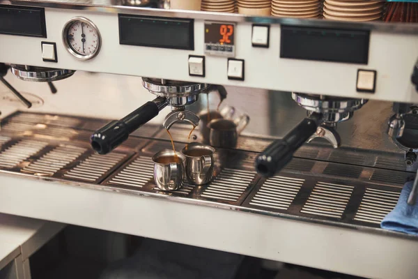 Espresso aromático goteando en dos tazas de la máquina de café —  Fotos de Stock