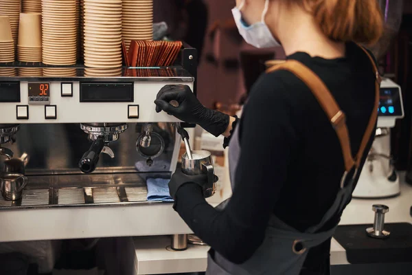 バリスタの制服を着た若い女性がコーヒーマシンを操作 — ストック写真