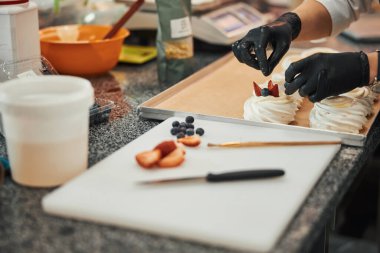 Kalifiye aşçı kremalı tatlıya biraz çilek ve fındık ekliyor.