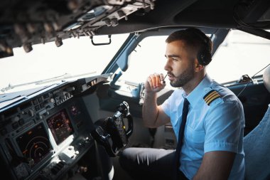 Ciddi bir pilot mikrofonda iş arkadaşlarıyla konuşuyor.