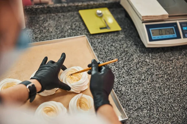 Pastelero profesional que añade glaseado y glaseado a los merengues blancos —  Fotos de Stock