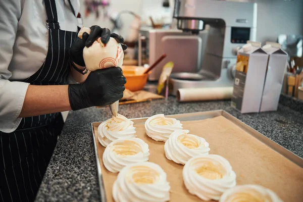 Titiz hamur işi şefi Pavlova tatlılarına krema ekliyor. — Stok fotoğraf