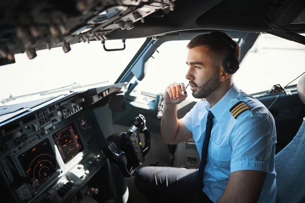 Seriös pilot som pratar med medarbetarna i mikrofonen — Stockfoto
