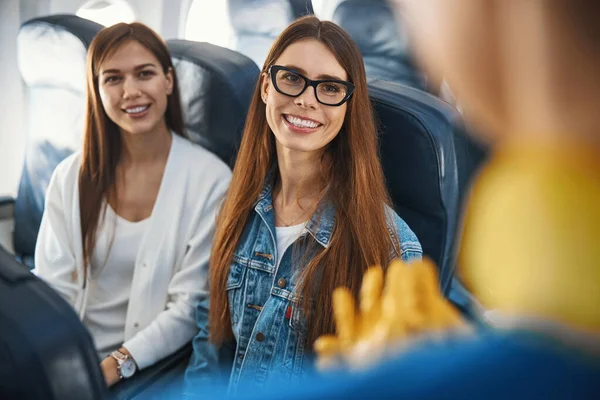 Vriendelijke dames die glimlachen naar de stewardess tijdens de vlucht — Stockfoto