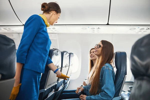 Две красивые дамы улыбаются дружественной стюардессе — стоковое фото