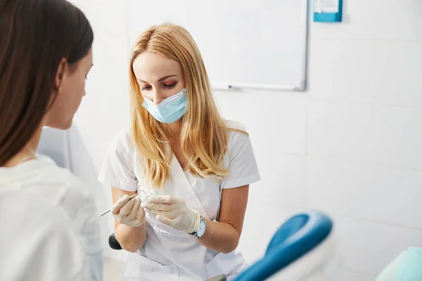 Mulher médica especialista apontando para a mandíbula moldada com sonda dentária — Fotografia de Stock