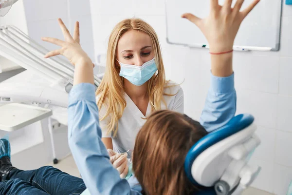 Playful child patient raising arms in the air before stomatologist — Stock Photo, Image