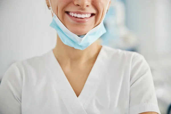 Посмішка працівника стоматологічної лікарні зі скинутою маскою — стокове фото